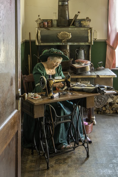 woman in period costume sitting at antique sewing table in mekiwin manor